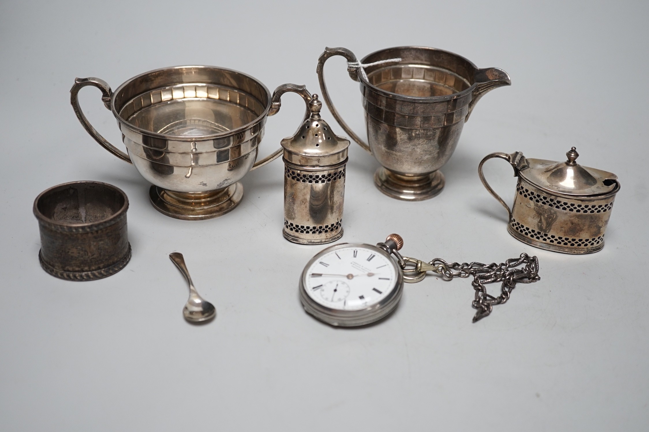 Small silverware, including a George V cream jug and matching sugar bowl, a mustard pot and matching pepper pot, silver serviette ring and a gentleman’s silver pocket watch and chain.